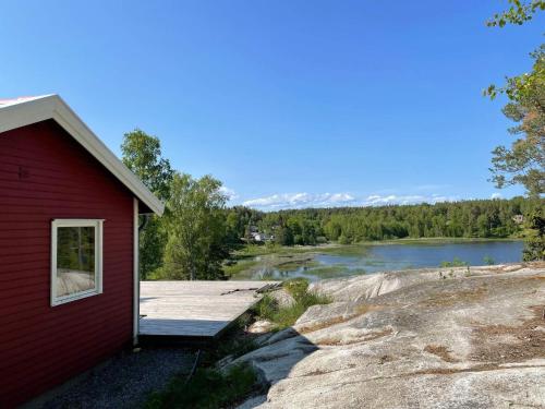 a red building with a deck next to a lake at 6 person holiday home in ÅKERSBERGA-By Traum in Åkersberga