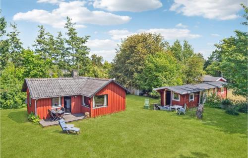 a red cabin in a field with a yard at Three-Bedroom Holiday Home In Nakskov in Nakskov