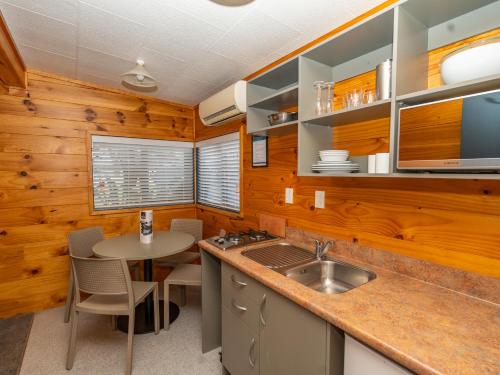 a kitchen with wooden walls and a table and a sink at Tasman Holiday Parks - Rotorua in Rotorua