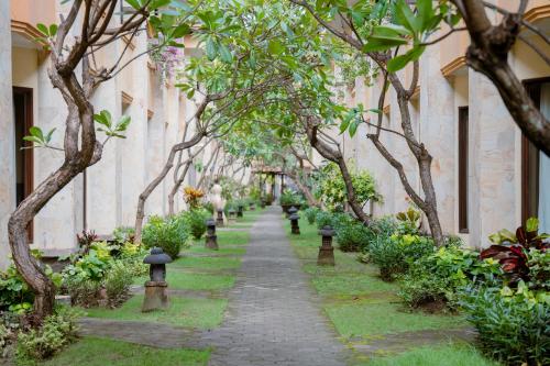 a walkway through a building with trees and plants at Pelangi Bali Hotel & Spa in Seminyak