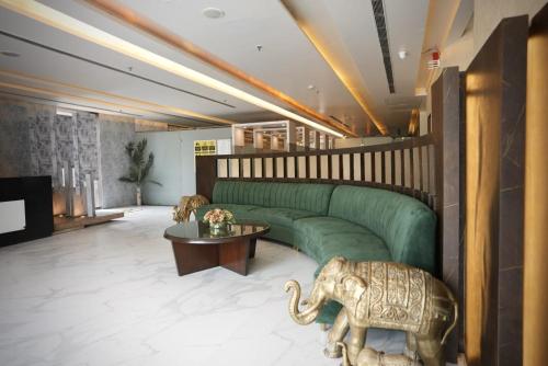 a living room with a green couch and an elephant statue at Hotel Windsor Heights in Gurgaon