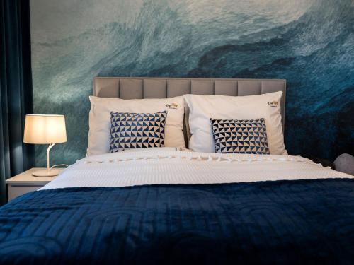ein Schlafzimmer mit einem Bett mit Kissen und einem Gemälde in der Unterkunft A comfortable apartment very close to the seaside beach, Niechorze in Niechorze