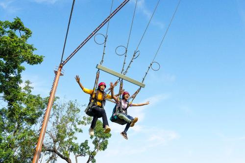 two people jumping in the air on a zip line at Whistling Woodzs Resort in Dandeli