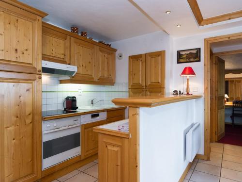 une cuisine avec des armoires en bois et un comptoir dans l'établissement Courchevel 1850 - Appartement cosy 50m² - 4 pers - centre station - proche pistes - FR-1-631-145, à Courchevel