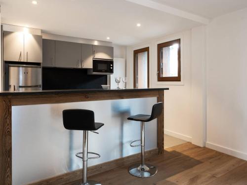 une cuisine avec deux tabourets de bar à un comptoir dans l'établissement Appartement rénové 88m2 au centre de Courchevel 1850 - 8 pers, parking, balcon, WIFI - FR-1-631-146, à Courchevel