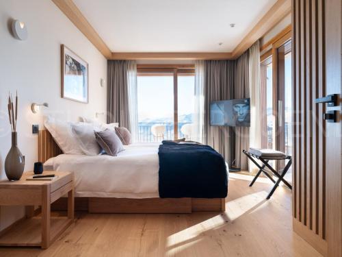 une chambre avec un lit et une grande fenêtre dans l'établissement Chalet au pied des pistes avec espace détente et home cinéma, 6 chambres, 14 pers - FR-1-686-29, à Arc 1800