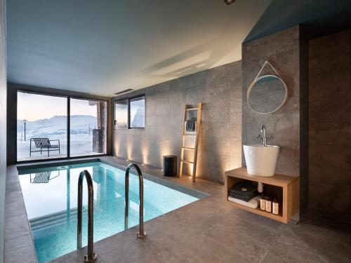 La salle de bains est pourvue d'une piscine avec une baignoire et un lavabo. dans l'établissement Chalet luxe 12 pers avec piscine, sauna, hammam, home cinéma et ski aux pieds à Arc 1800 - FR-1-686-30, à Arc 1800