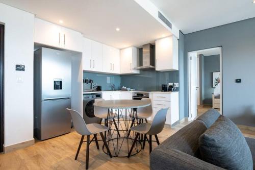 een keuken en een woonkamer met een tafel en stoelen bij Oceans Umhlanga 2 Bedroom Accommodation in Durban