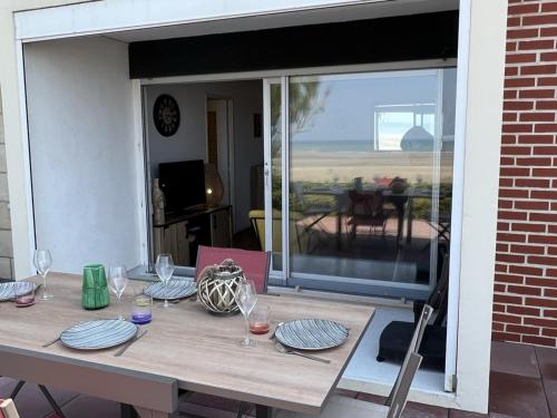 - une table avec des verres et des assiettes sur la terrasse dans l'établissement Appartement 2P, Rez-de-jardin, Accès Plage, Animaux OK, Parking, Internet Inclus - FR-1-487-355, à Cabourg
