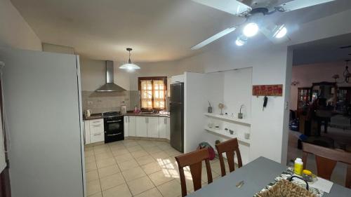 una cocina con armarios blancos y una mesa con sillas. en Casa Upcn en La Rioja