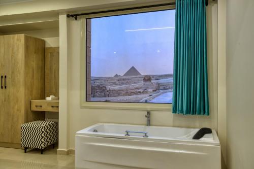 a bathroom with a tub and a window with a pyramid at The Gate Hotel Front Pyramids & Sphinx View in Cairo