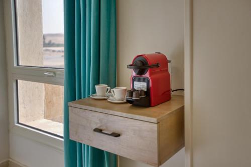 a red espresso machine sitting on a table next to a window at The Gate Hotel Pyramids in Cairo
