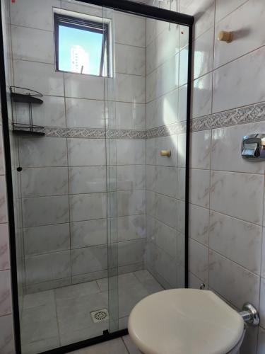 a bathroom with a shower with a toilet and a window at 2 quartos a 200mts praia Central, GARAGEM, CHURRASQUEIRA, WI-FI 90 Mbps, PET FRIENDLY in Balneário Camboriú