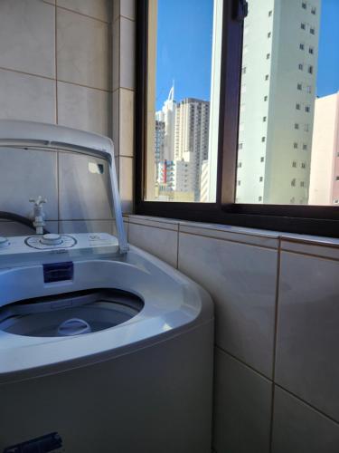 a bathroom with a white sink and a window at 2 quartos a 200mts praia Central, GARAGEM, CHURRASQUEIRA, WI-FI 90 Mbps, PET FRIENDLY in Balneário Camboriú