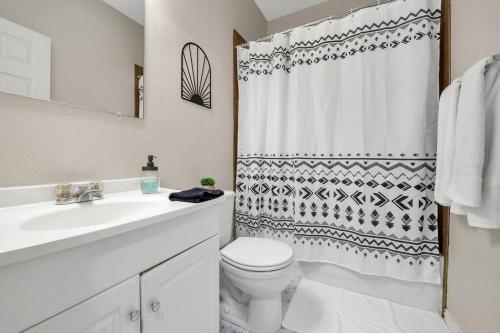 a white bathroom with a toilet and a shower curtain at Taste of Everything House 5 from Baylor & Magnolia in Waco