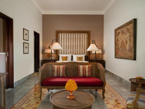a bedroom with a bed and a couch and a table at Sudamala Resort, Sanur, Bali in Sanur