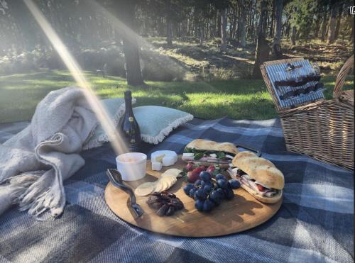 a plate of food with a sandwich and grapes on a picnic blanket at Daylesford FROG HOLLOW ESTATE- The Retreat in Daylesford