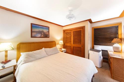 a bedroom with a bed and a desk and a window at Partial Oceanview 1BR at Kiahuna Plantation Unit 311 in Koloa