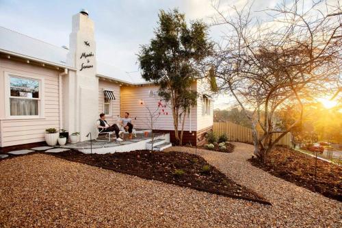 two people sitting on the porch of a house at Months and Seasons Design-led Country House in Daylesford