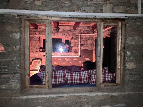 a window in a brick wall with a bed in a room at Shoonya Home Stay - Devalsari Deodar Forest Range - 60min from Mussoorie in Mussoorie