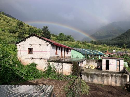 an old building with a rainbow in the background at Shoonya Home Stay - Devalsari Deodar Forest Range - 60min from Mussoorie in Mussoorie