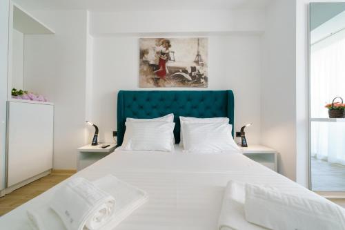 a bedroom with a large white bed with a blue headboard at Afrodita Infinity Beach Pool&Spa Mamaia Nord in Mamaia Nord
