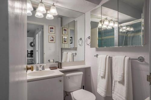 a bathroom with a toilet and a sink and a mirror at Tranquil 2BR downtown condo, Parking, King bed in Seattle
