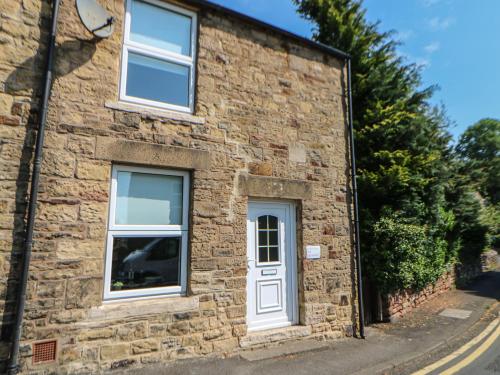 a brick house with a white door and windows at Hollie Cottage in Haltwhistle