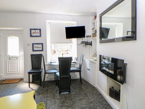 a living room with a table and chairs and a television at Hollie Cottage in Haltwhistle