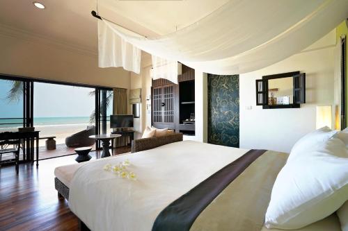 a bedroom with a large bed with a view of the ocean at Praseban Resort in Pran Buri