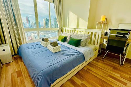1 dormitorio con cama con sábanas azules y ventana en High-Class 2BED Condo Just 1-Step from BTS ONNUT en Bangkok