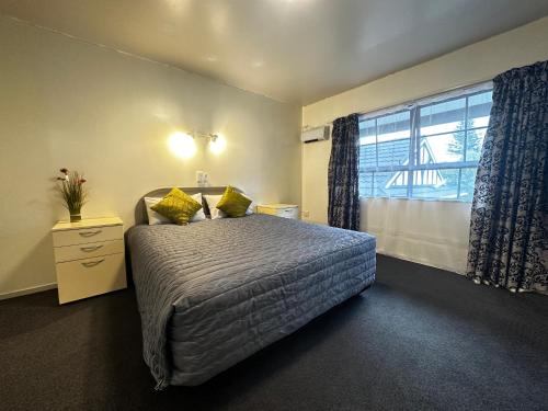 a bedroom with a bed and a large window at Kingswood Manor Motel in Whangarei