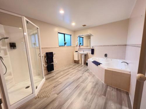 a bathroom with a shower and a tub and a sink at Kingswood Manor Motel in Whangarei