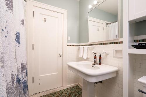 ein weißes Badezimmer mit einem Waschbecken und einem Spiegel in der Unterkunft Twin City Terrace in Minneapolis
