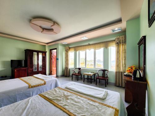 a bedroom with two beds and a table with chairs at Nhật Anh Hotel Cát Bà in Cat Ba
