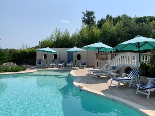 a swimming pool with chairs and umbrellas at Villa des Sapins in Peymeinade