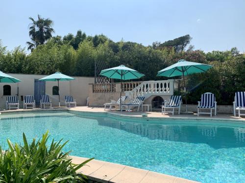 una piscina con sillas y sombrillas en Villa des Sapins en Peymeinade