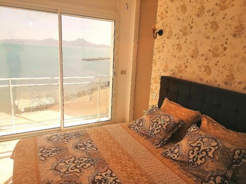 um quarto com uma cama e vista para a praia em La perle bleue em La Goulette