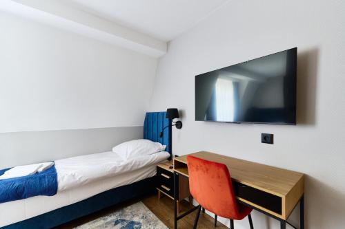 a room with a bed and a desk and a television at Apartamenty Na Skarpie in Płock