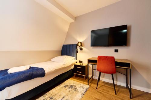 a hotel room with a bed and a desk and a television at Apartamenty Na Skarpie in Płock