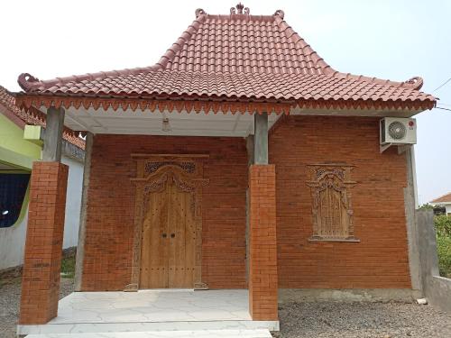 une maison en briques avec une porte en bois et un toit dans l'établissement Hexa Jongkangan, à Bugisan