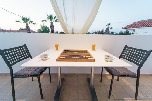 a white table with two chairs and a table with cups on it at PEDRO NAVARINO ΙΙΙ Laganas in Laganas