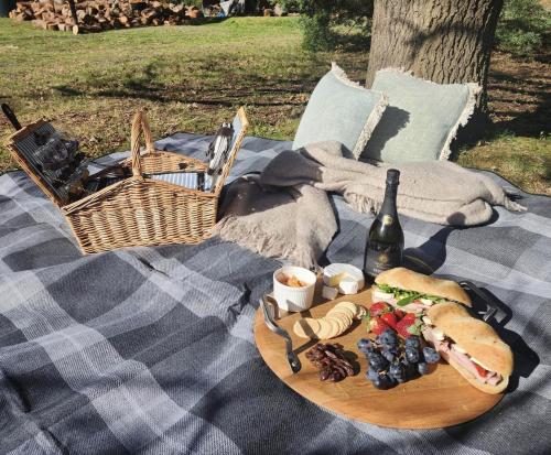 a picnic table with a plate of food and a bottle of wine at DAYLESFORD Frog Hollow Estate THE BARN - Wanting a different experience - Stay in the Barn - Table Tennis Table - Cinema Projector - Bar - Wood Fireplace - 3 QUEEN BEDS - A fun place for everyone in Daylesford
