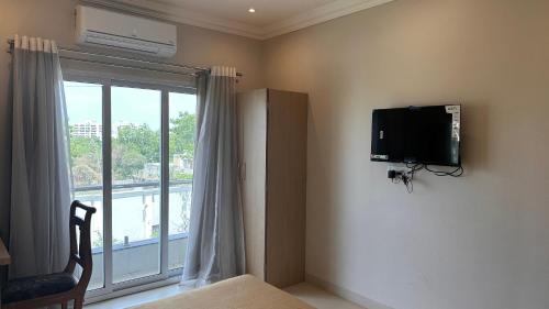 a bedroom with a tv on the wall and a window at Hotel Unnati in Aurangabad