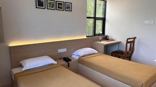 een kamer met 2 bedden, een stoel en een raam bij Hotel Unnati in Aurangabad