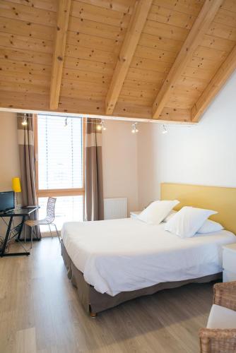 un grand lit dans une chambre avec un plafond en bois dans l'établissement Ame de la Terre, à Ruffey-lès-Échirey