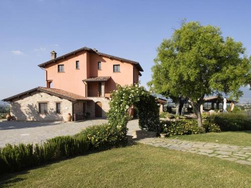 a large house with a tree and a grass yard at Holiday apartment on a farm in Umbria in Bettona