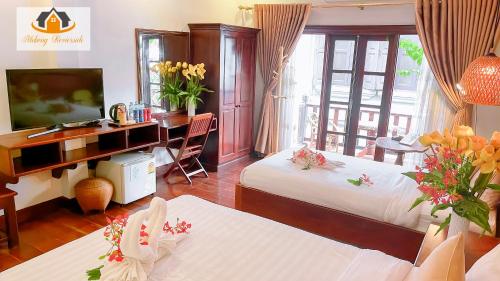 a hotel room with two beds and a desk at Mekong Charm Riverside in Luang Prabang