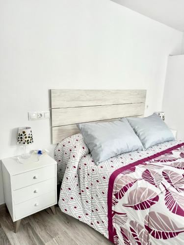 a white bedroom with a bed and a white nightstand at Bajo torreón in Setenil