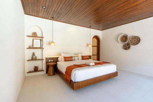 a bedroom with a large bed with a wooden ceiling at Green Jimbaran Bay Villa in Jimbaran